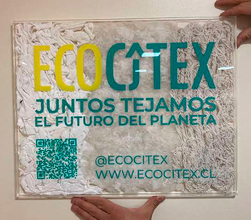 Cuadro de exhibición en acrílico con material reciclado y logo en vinilo troquelado.