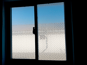 Vinilo empavonado con diseño personalizado para privacidad en ventanas de baños. Soluciones de Privacidad Filingraf
