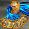 Pila turro de medallas de acrílico doble capa con cinta, apoyada sobre un abanico de medallas en la base, listas para despacho por Filingraf vía Blue Express.
