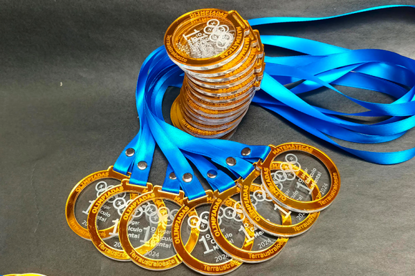 Pila turro de medallas de acrílico doble capa con cinta, apoyada sobre un abanico de medallas en la base, listas para despacho por Filingraf vía Blue Express.