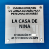 Vista frontal de letrero ELEAM en acrílico blanco de 5mm con gráfica normativa negra y fijaciones metálicas.